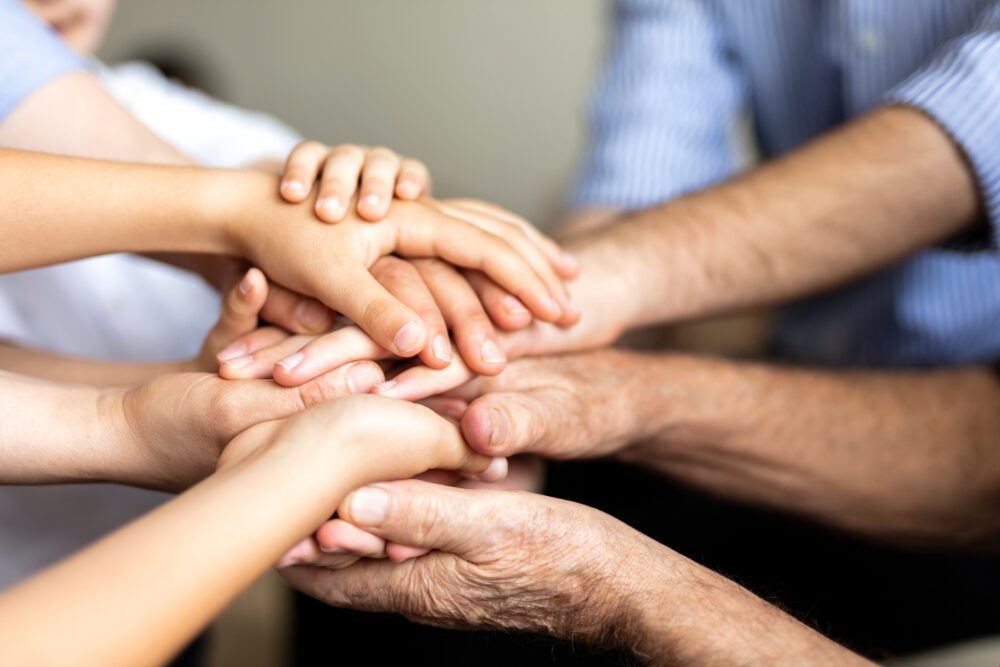 Multiple hands gently holding each other symbolizing support and unity.