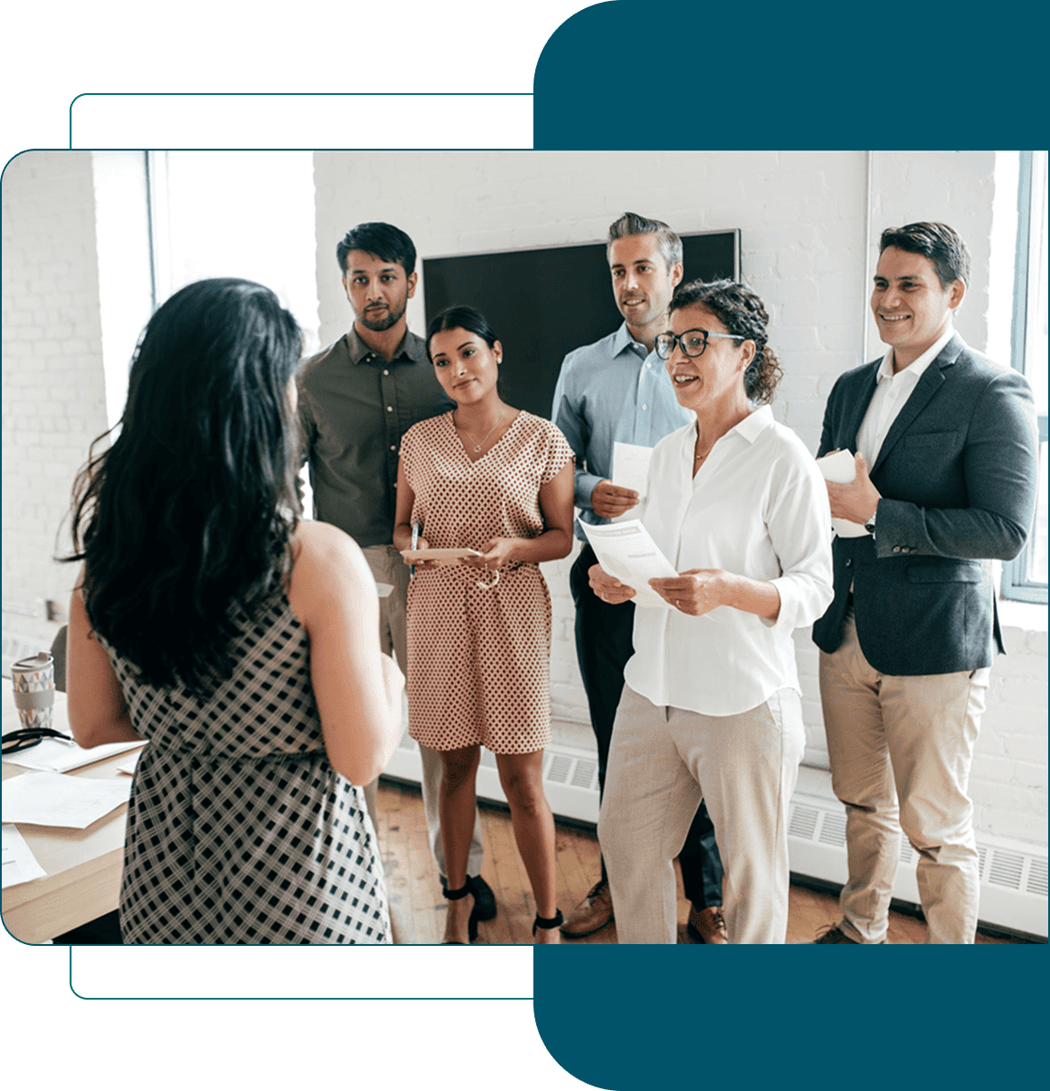 A group of young professionals engaged in a discussion led by a woman.