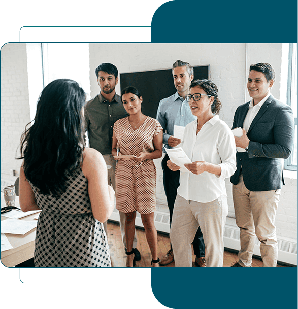 A woman presenting to four attentive colleagues in a modern office.