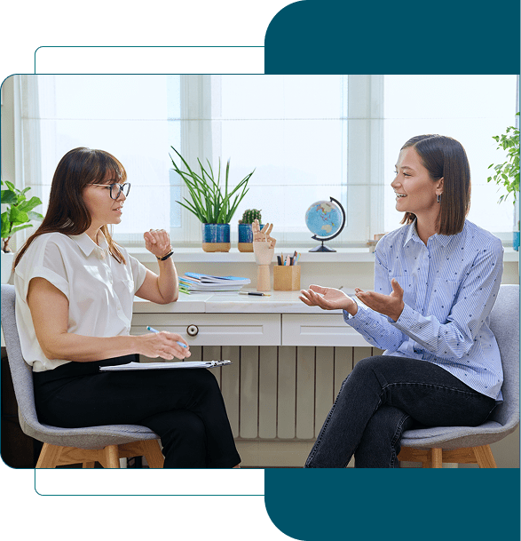 Two women engaged in a friendly conversation in a bright office.