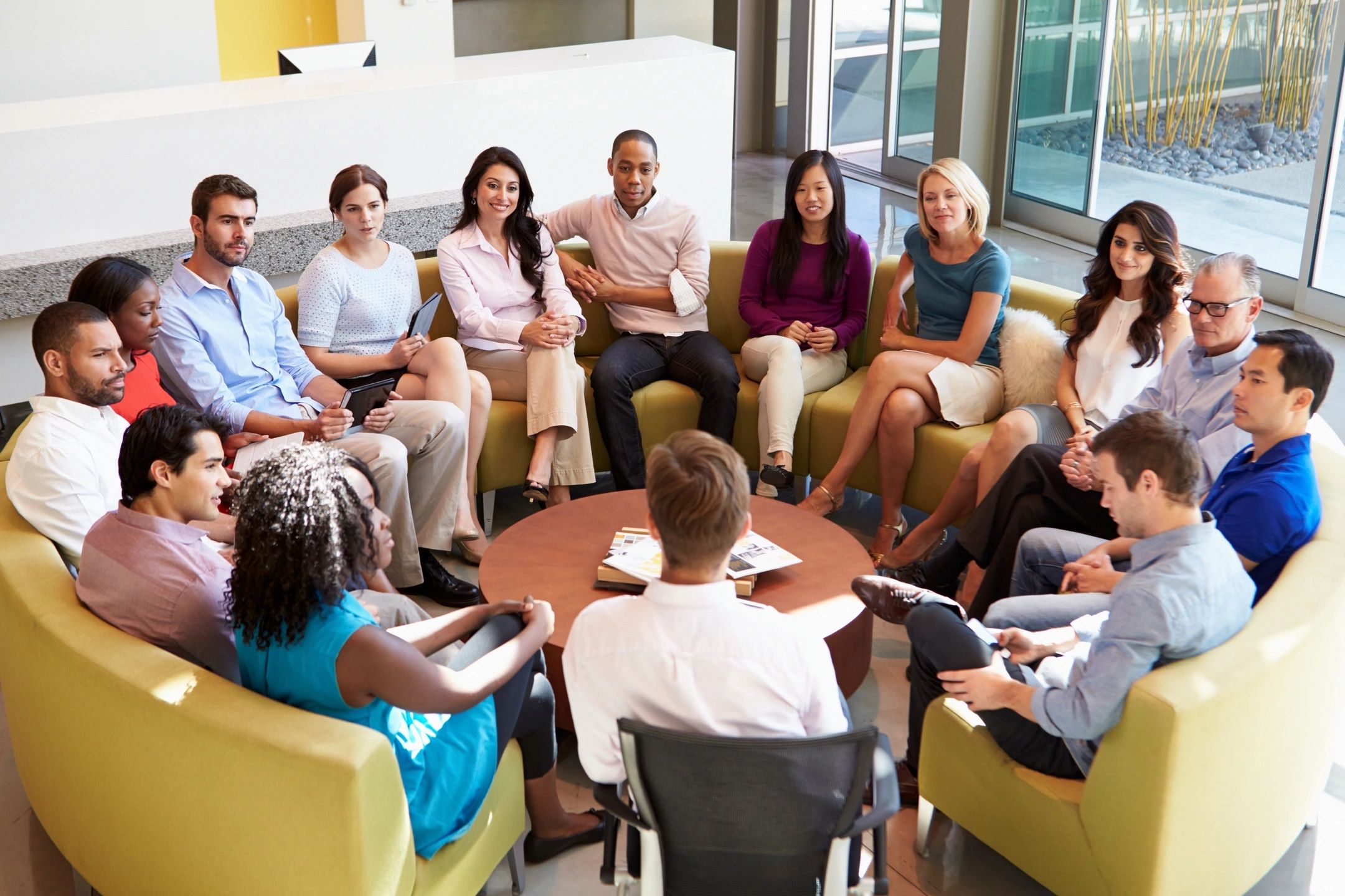 A diverse group engaged in a collaborative meeting in a bright room.