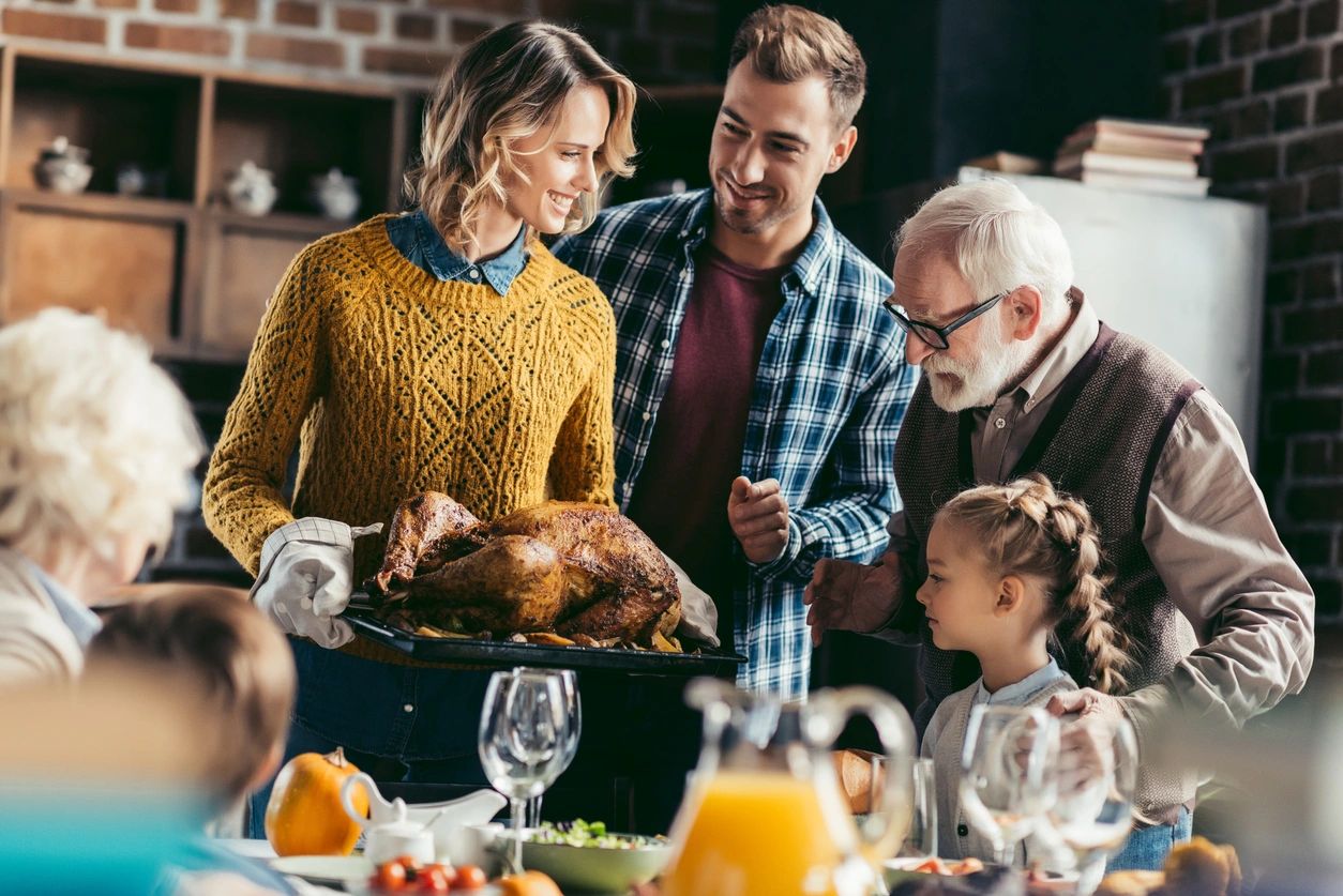 Family enjoying a festive meal together, carving a roast turkey.